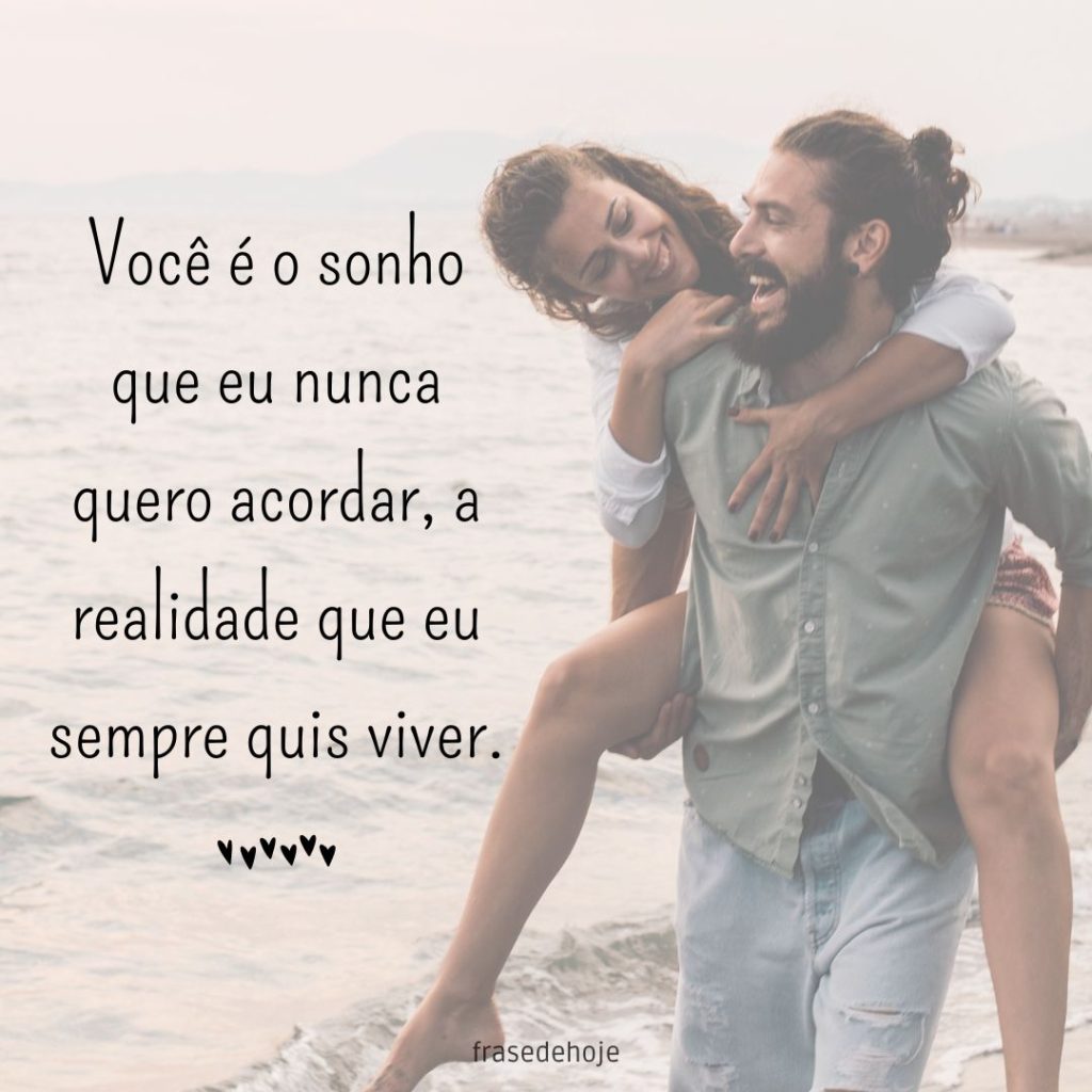 Casal feliz na praia com uma frase de amor ao lado