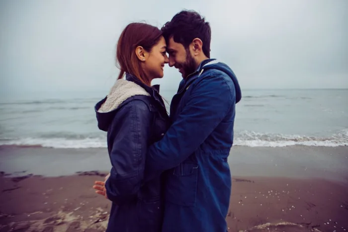 frases de amor para expressar seus sentimentos: casal feliz num dia frio na beira da praia.